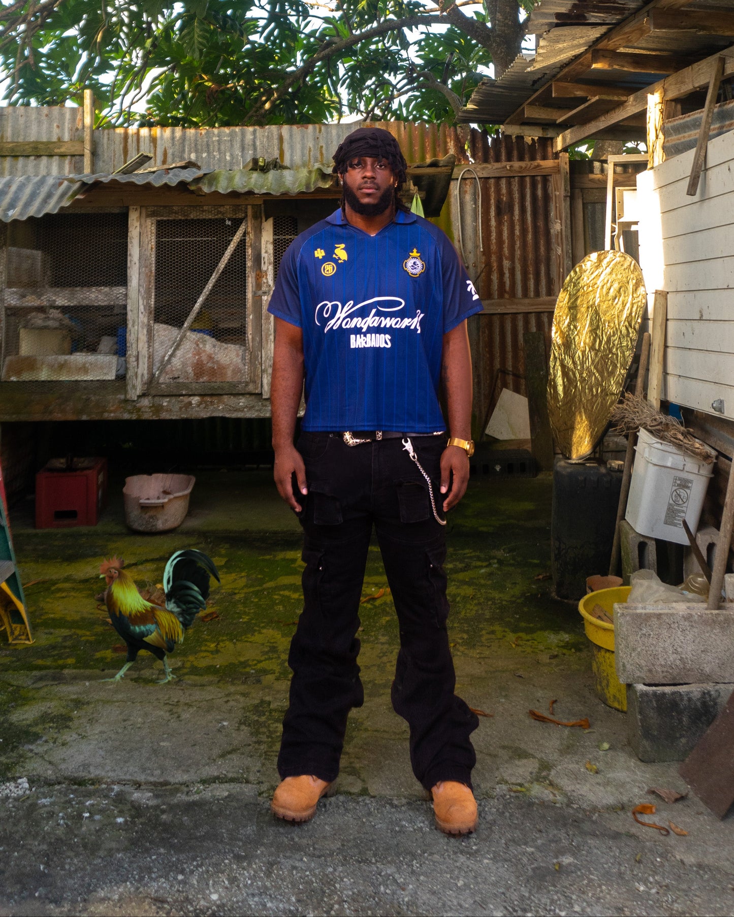 Person wearing a blue shirt standing in front of a wooden structure with trees in the background
